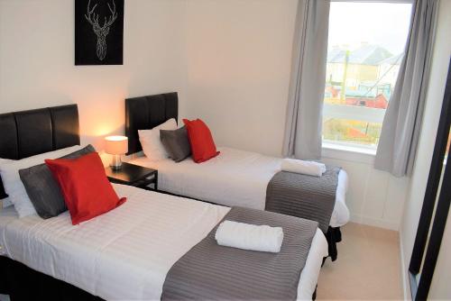 格兰奇茅斯Kelpies Serviced Apartments MacGregor- 2 Bedrooms的酒店客房设有两张床和窗户。