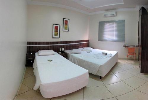 多拉杜斯Dourados Center Hotel的一间设有两张床和一张桌子的房间