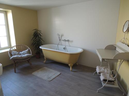 欧迪耶讷La Quincaillerie的带浴缸、椅子和桌子的浴室