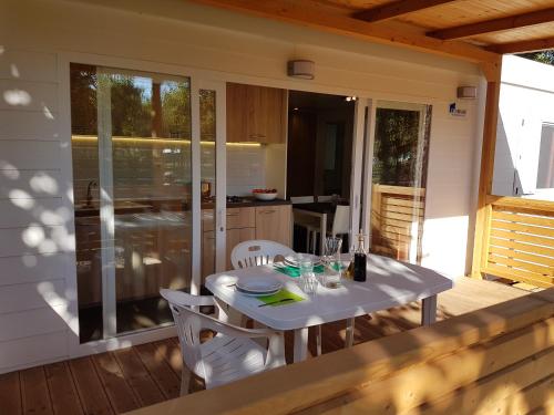 马里纳迪马萨Camping Taimì的甲板上配有白色的桌椅和厨房