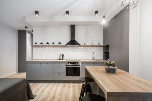 维尔纽斯Uptown studio apartment的厨房配有白色橱柜和木制台面