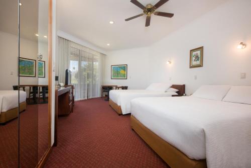 Santo DomingoHotel Bougainvillea San José的酒店客房设有两张床和电视。