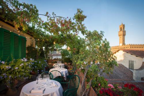 佛罗伦萨赫米缇吉酒店的一个带桌椅的庭院和钟楼