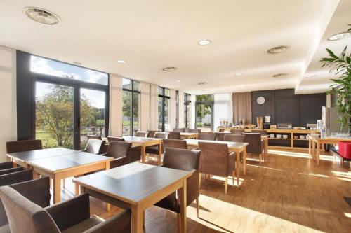 里昂里昂市奥德利生物园公寓式酒店的餐厅设有木桌、椅子和窗户。