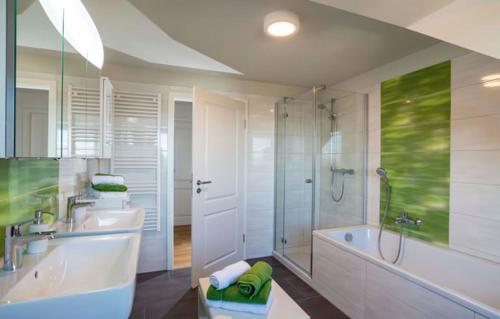弗赖贝格Hotel Freyhof的浴室配有2个盥洗盆、浴缸和淋浴。
