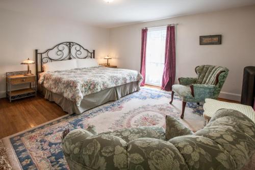 Margaretville乡村套房酒店的一间卧室配有一张床、一张沙发和一把椅子