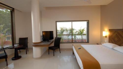 舍地Sai Palace Budget Hotel的一间卧室配有一张床、一张书桌和一台电视