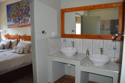 奥奇瓦龙戈Kamaku Guesthouse的一间带两个盥洗盆和镜子的浴室以及一张床