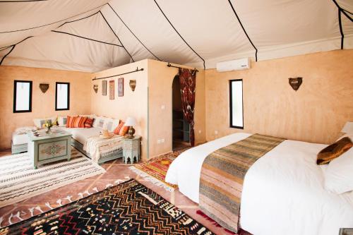 Douar Caïd LayadiVilla Dinari的一间卧室配有一张床,一张沙发位于帐篷内
