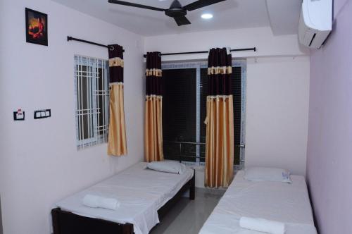 蒂鲁帕蒂SGS Residency的客房设有两张床和一个带窗帘的窗户。