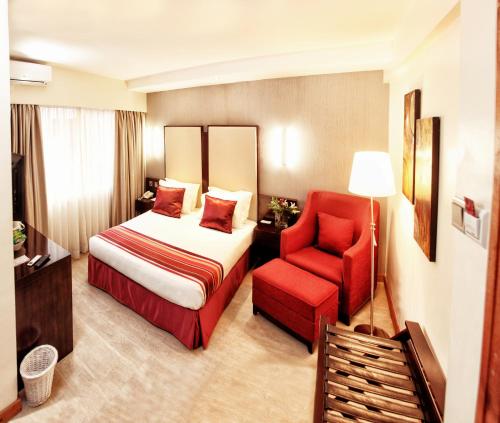 内罗毕The Zehneria By Sarovar Portico India的酒店客房,配有一张床和一张红色椅子