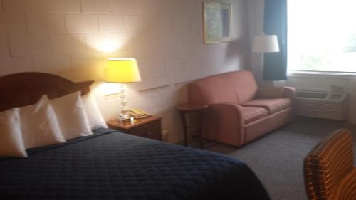 Mound CityAudrey's Motel的一间卧室配有一张床、一把椅子和一盏灯