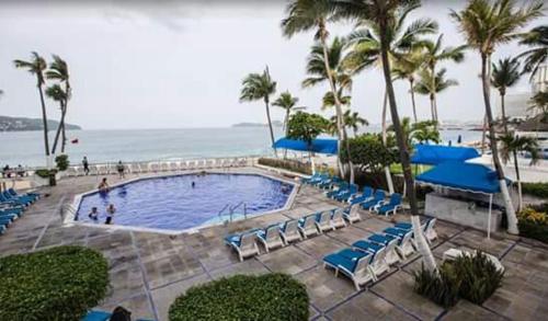 阿卡普尔科阿卡普尔科马里布酒店的一个带蓝色椅子的游泳池以及大海