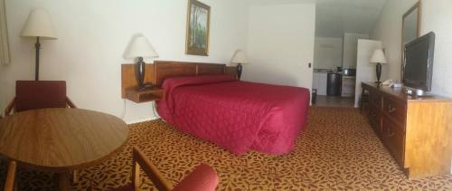 费尔普莱Western Inn Motel & RV Park的酒店客房配有红色的床和一张桌子