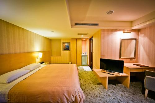 淡水和昌商旅淡水馆的酒店客房配有一张床、一张书桌和一台电视。