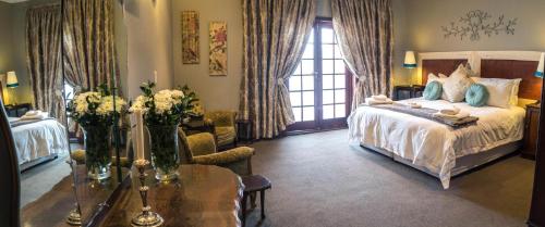 卡利南Premier Hotel and Spa Cullinan的一间卧室配有一张床和一张鲜花桌子