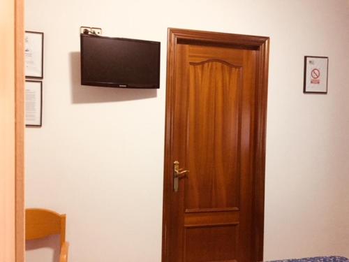 特拉萨Hostal del Carmen的木门,墙上配有平面电视