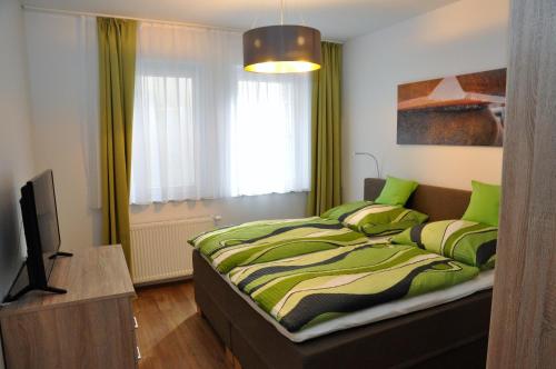威斯巴登奎林公寓的一间卧室配有一张带绿色床单的床和电视。