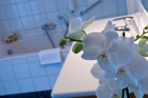 布尔沙伊德可库恩酒店的浴室里一束白色的花坐在柜台上