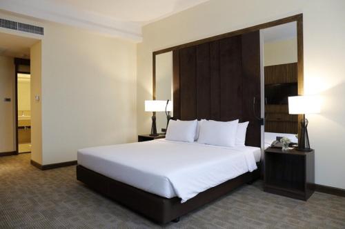 曼谷Louis Tavern Hotel的酒店客房设有一张大床和两盏灯。