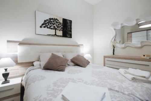 塞维利亚Luxury Apartment Peñuelas Free Parking的卧室配有一张带镜子的白色床