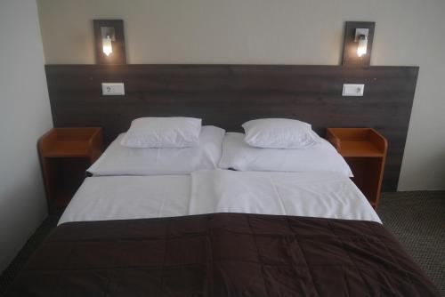 巴拉顿菲赖德Hotel Tagore的一张带两个白色枕头的床和两个床头柜