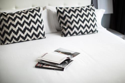 马德里珀蒂宫翠柏酒店的一张带黑白枕头的床和一堆杂志