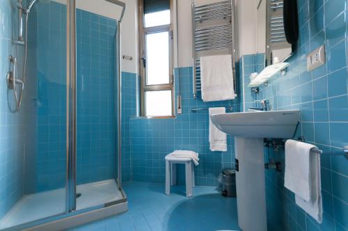 那不勒斯阿尔宾娜酒店的蓝色瓷砖浴室设有水槽和淋浴