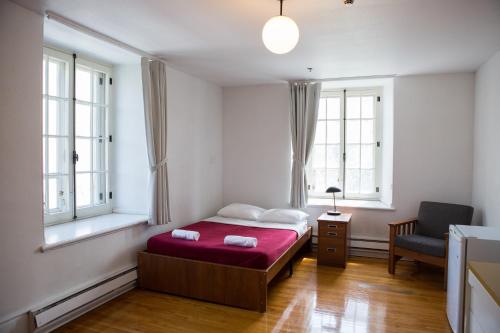 蒙特利尔The Grey Nuns Residence by Concordia University的一间卧室配有一张床和一把椅子,还有两个窗户