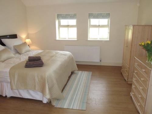 比代尔Little welham的一间卧室配有一张床、一个梳妆台和两个窗户。