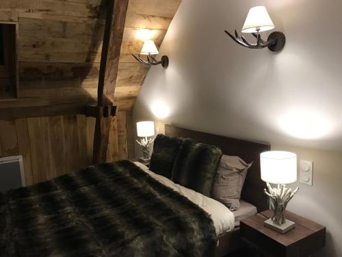 特拉松Les Maisons du Périgord的卧室配有一张床,墙上有两盏灯