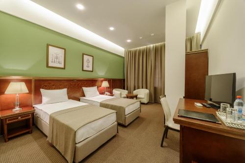 敖德萨Alarus Luxe Hotel的酒店客房配有两张床和一张书桌