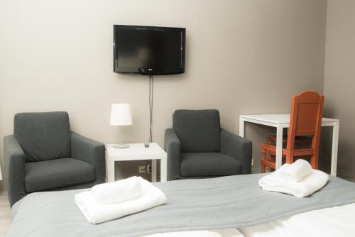 奥普达尔Oppdal Gjestetun Hotell的一间卧室配有两把椅子、一张床和一台平面电视。