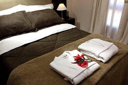 圣尼古拉斯De Los Arroyos Apart Hotel的床上有毛巾和鲜花