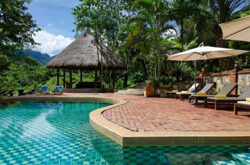 琅勃拉邦山林自然生活方式酒店的毗邻度假酒店的带椅子和遮阳伞的游泳池