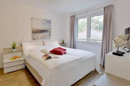 朱列斯拉赫Ferienwohnung Seestern的白色卧室配有一张带红色枕头的大白色床