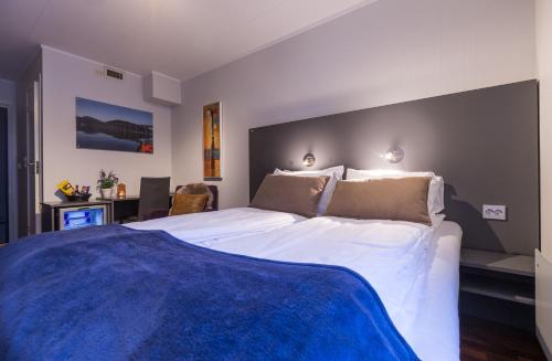 特罗姆瑟恩特维京酒店的一间卧室配有一张带蓝色毯子的大床