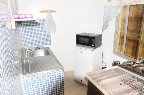 Fajara雷布托海滩酒店的厨房配有水槽和冰箱上的微波炉