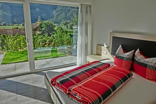 卡斯泰尔贝洛Weinreichhof的一间卧室配有一张带红色枕头的床和大窗户