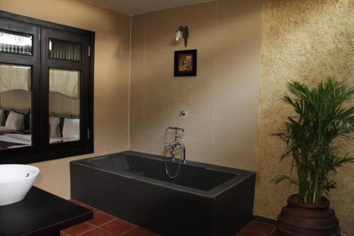 美奈莲花村度假酒店的一间带大型黑色浴缸和植物的浴室