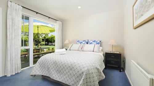 基督城橄榄树住宿加早餐酒店的一间卧室配有一张床,窗户配有雨伞