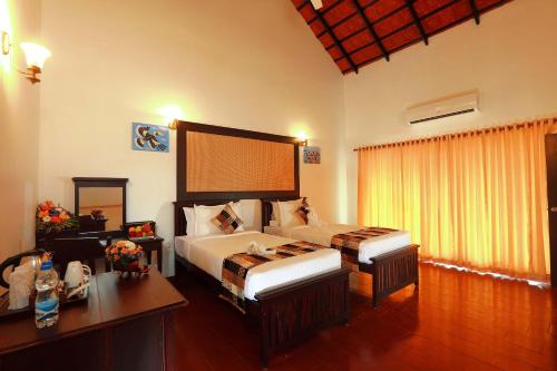 科钦Nihara Resort and Spa Cochin的一间卧室配有两张床、一张桌子和一张书桌