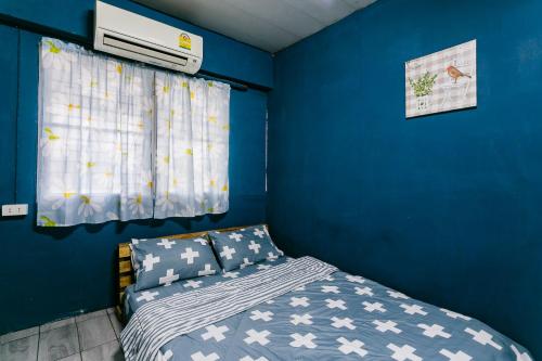 南邦Malai Place Lampang的卧室设有蓝色的墙壁、一张床和一个窗户