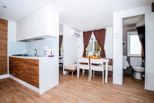 宁Zaton Holiday Resort Mobile Homes的厨房以及铺有木地板的用餐室,配有白色的墙壁。