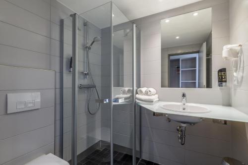 埃尔森贝格Hotel Irschenberg Süd的带淋浴、盥洗盆和镜子的浴室