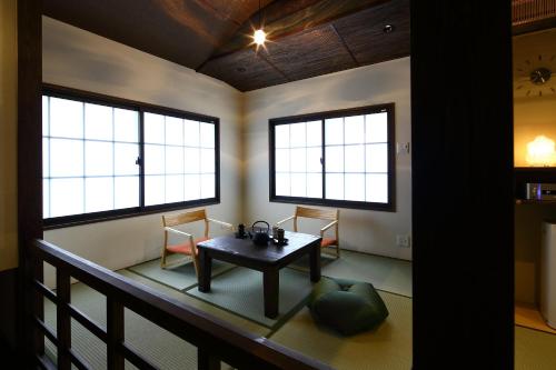 京都Machiya Kaemon的一间设有桌子和两把椅子以及两个窗户的房间