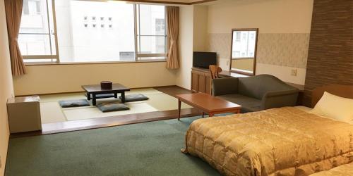 伊东伊藤园酒店的一间卧室配有一张床、一张沙发和一台电视。