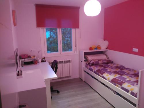 潘普洛纳Apartamento Turístico Marcelo Celayeta AT Cerca del Centro的粉红色的客房设有一张床、一张桌子和一个柜台。