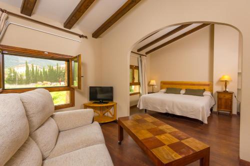 贝塞特丰特德尔柏斯酒店的一间卧室配有一张床、一张沙发和一台电视。