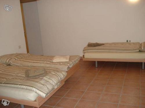 Brontallo鲁斯蒂科极光酒店的铺有瓷砖地板的客房内的两张床